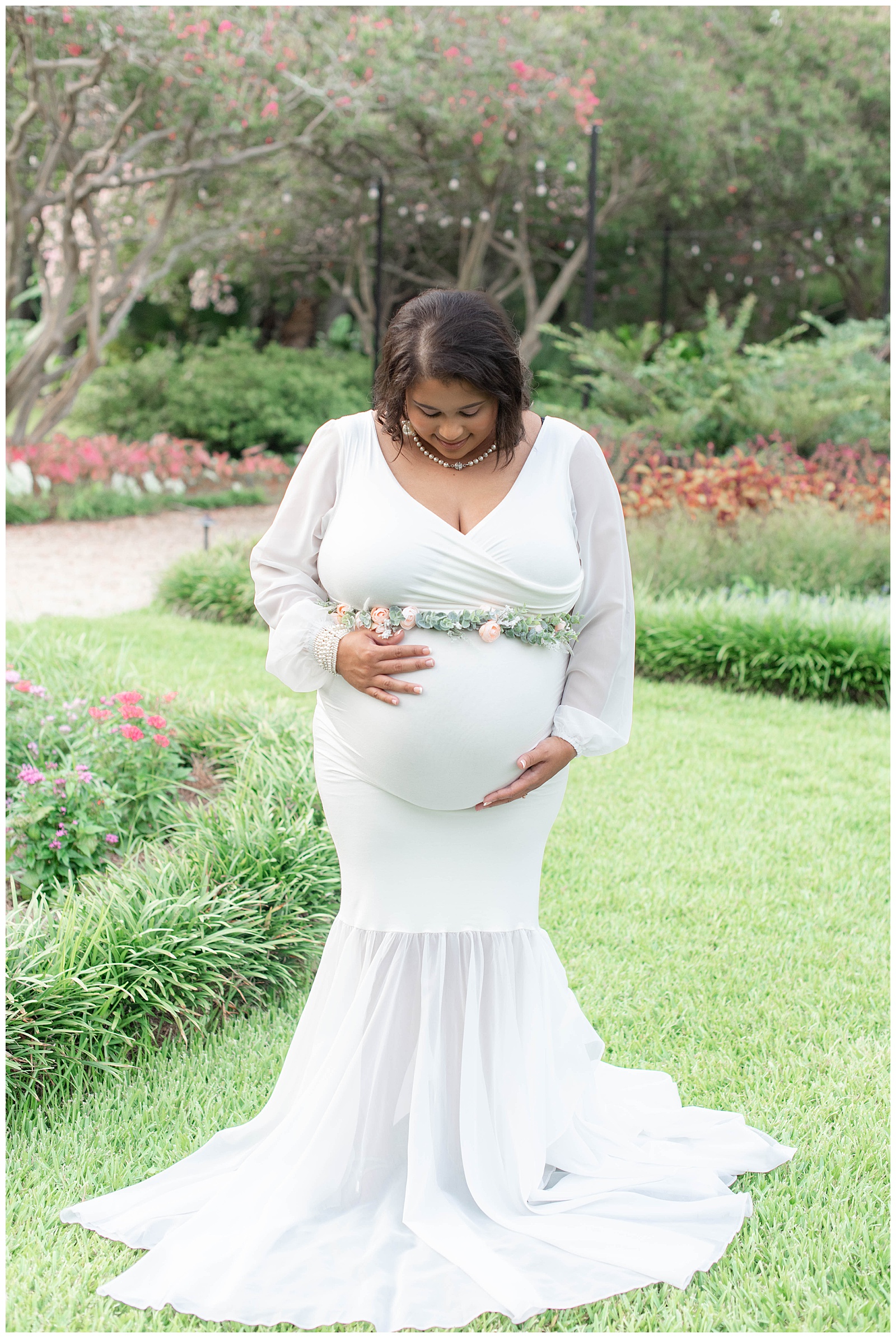 mom stares down at baby belly at the Orangerie gardens at Burden Center