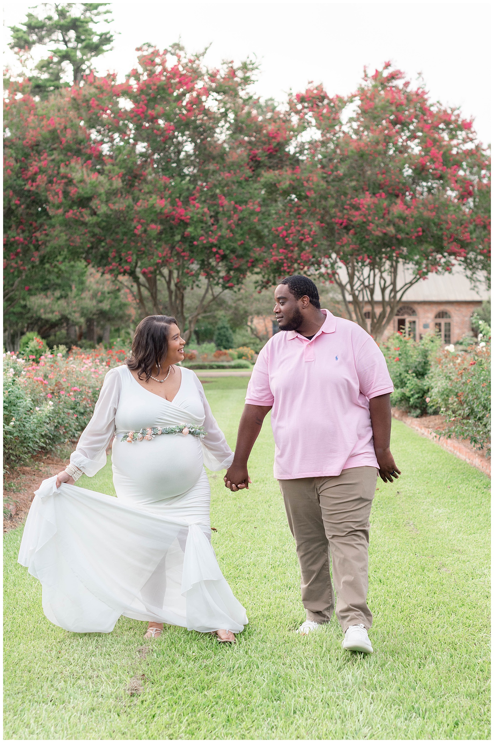 mom and dad walking and holding hands in rose garden at Burden Center