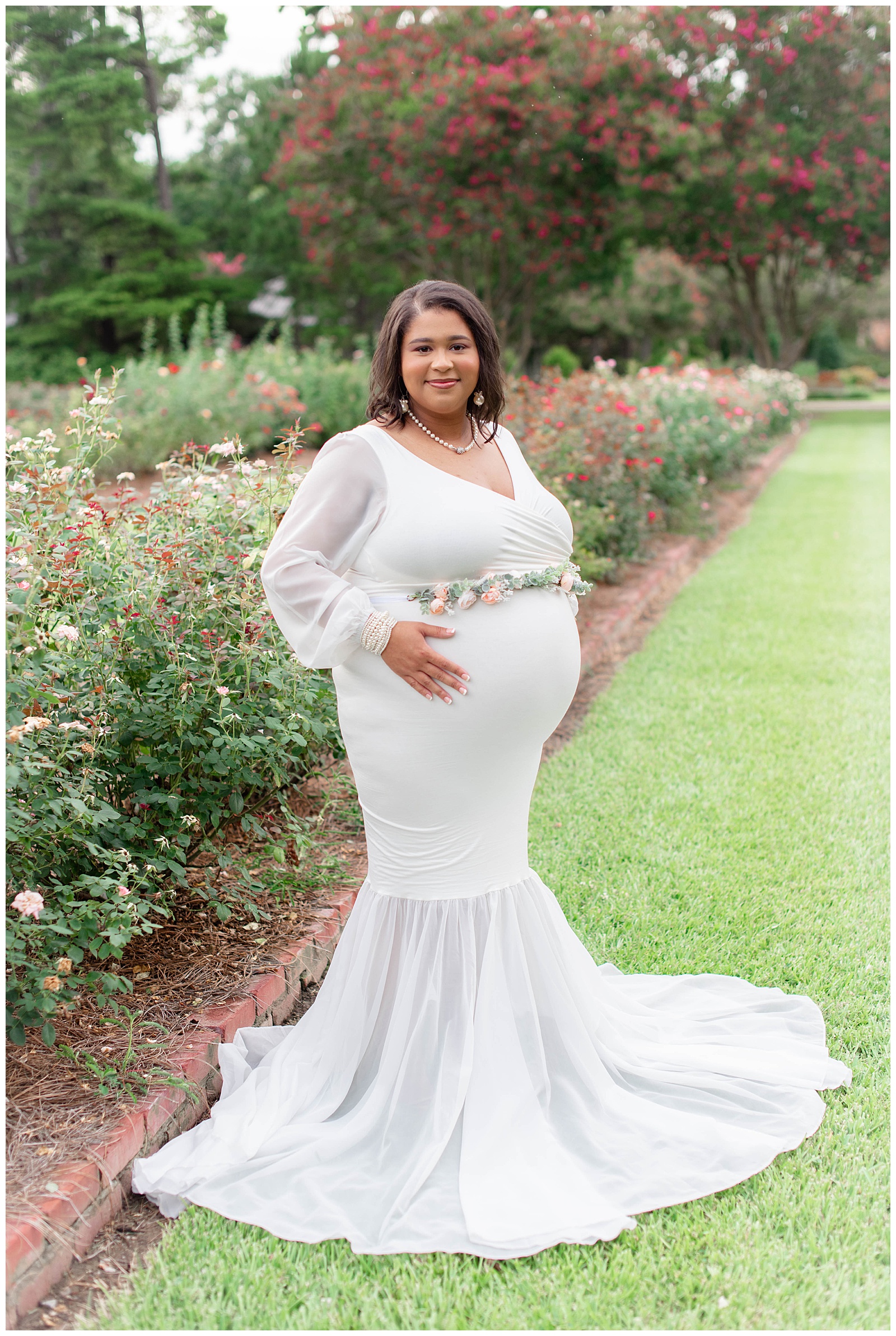 mom holds belly in rose garden at Burden Center