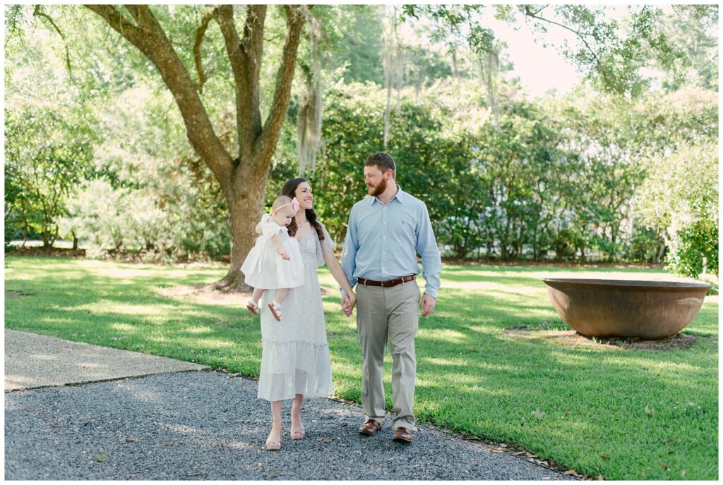 Baton Rouge Newborn Photographer - mom and dad smile at each other walking together with baby girl