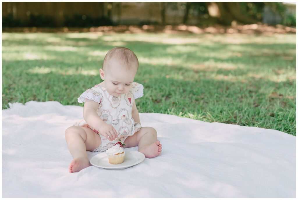 Baby girl reaching for cupcake at One-Year-Milestone-Session-Amanda-Higgins-Photography